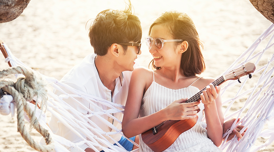A couple is playing a small Hawaiian guitar; image used for HSBC loans article - how to plan a dream wedding.