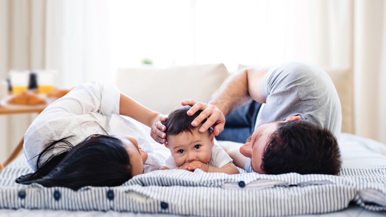 A family of three is lying comfortably in bed; image used for HSBC mortgages page.