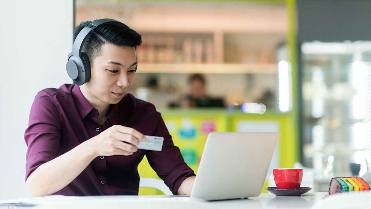 一位男士在咖啡廳裹用信用卡線上支付賬單；圖片使用於滙豐信用卡理財頁面。