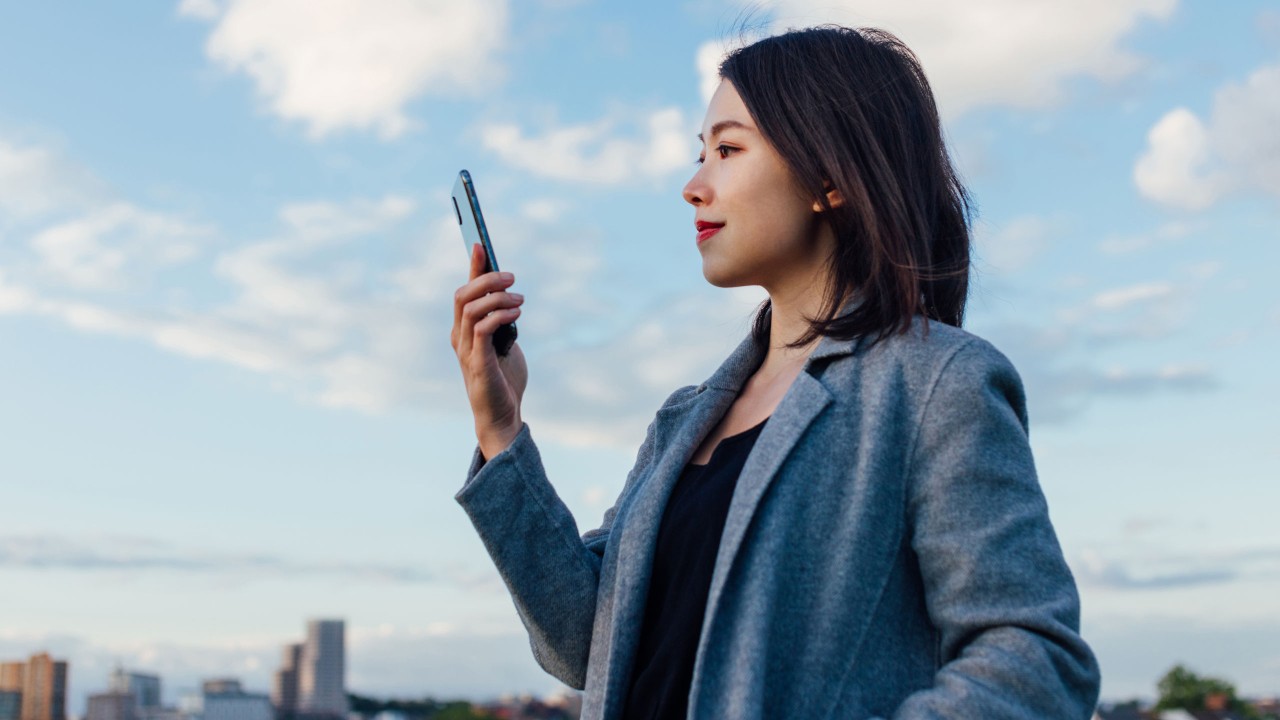 一位女士在藍天下使用手機; 圖片使用於帳單與繳費的頁面。